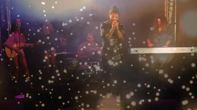 Singer holding mic, starting music; band playing, bokeh over stage, camera moving, boosting vocals