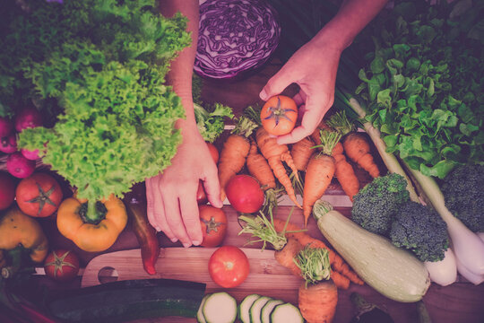 Hands sorting fresh vegetables on a market table for healthy cooking and salad preparation