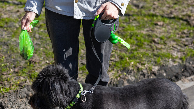 Woman with poop bag dispenser outdoors, responsible pet care, hygiene practice, urban service, cleanliness.