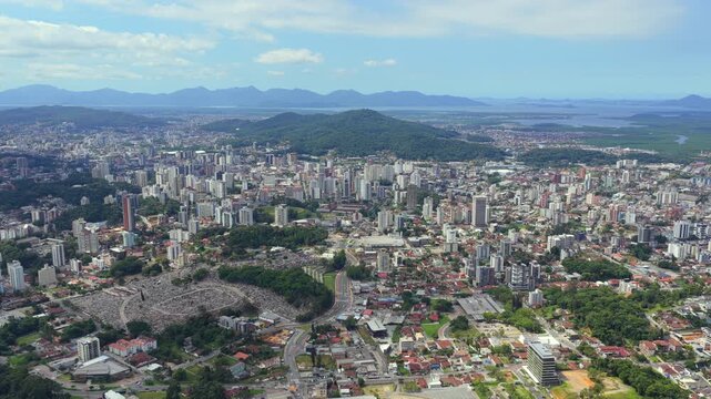 Panoramic aerial view of Joinville city with urban skyline and surrounding green hills.