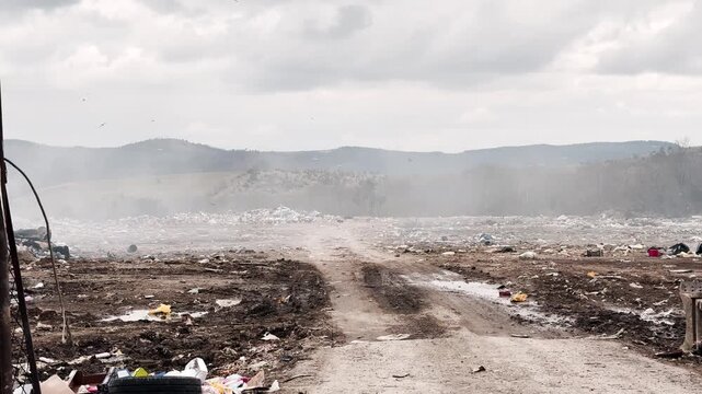 Burning landfill in Serbia with smoke and birds environmental pollution.Large garbage landfill in rural Serbia with smoking waste and flying birds. Environmental pollution and ecological problem 