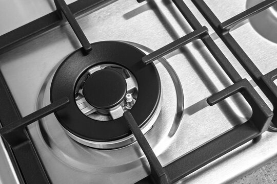 Top down close up of a modern stainless steel gas hob burner with cast iron grate in kitchen