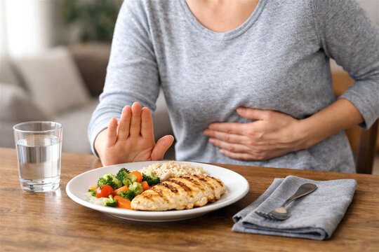 woman refusing meal due to stomach pain or indigestion. Girl holding belly with hand and making stop gesture. Concept of food intolerance, heartburn, gastritis or unhealthy digestive system