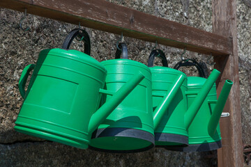 Green plastic watering cans hanging in row © WH_Pics