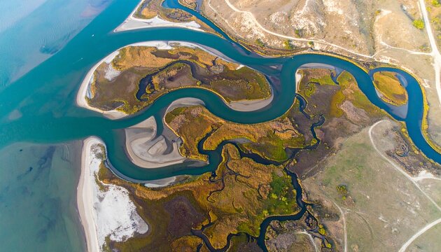 Aerial view of winding tidal creek in salt marsh with cordgrass and blue water channels