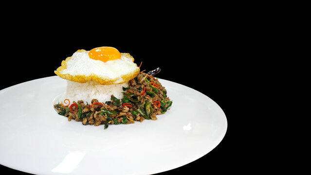 Pad Kra Pao, Thai stir-fried minced beef with holy basil and fried egg on black background.