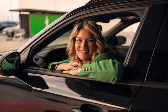 Woman smiling from car window wearing green jacket