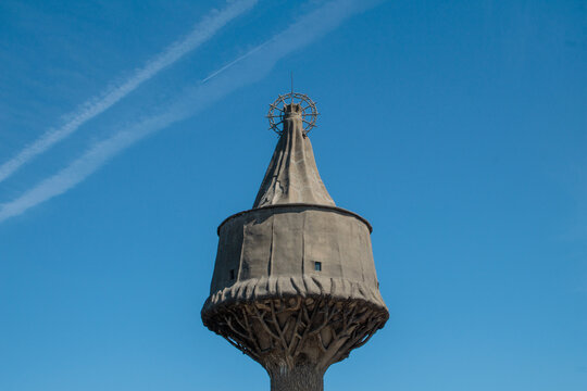Esta imagen muestra el Monumento a la Virgen de la Antigua en Cantabria, Espa&ntilde;a, bajo un cielo azul vibrante. La estructura de piedra &uacute;nica, con su distintiva forma de seta y el nicho de la Virgen, se