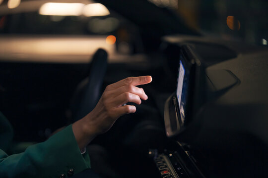 Hand touching car touchscreen display at night