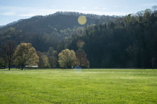 Late morning sun on grassy field with mountains in background from walking track along the Holston River at Laurel Run Park in Hawkins County, Church Hill, Tennessee.