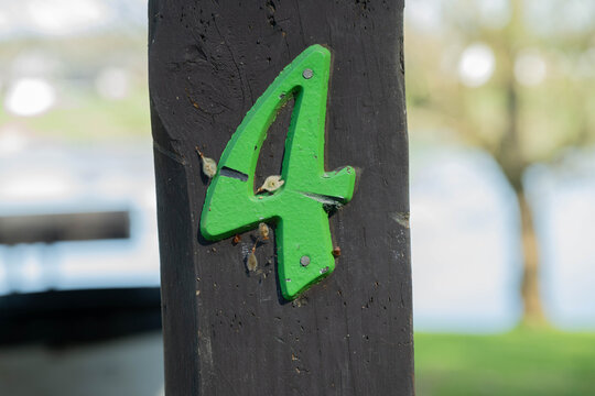 Number 4, bright green chippy, textured paint, grunge, on brown post.