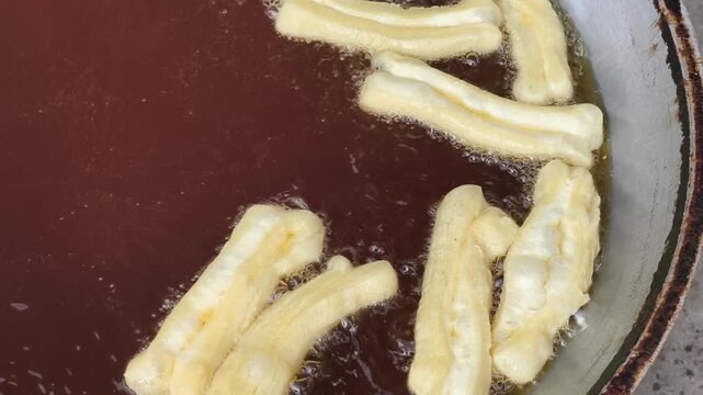 Close-up shot of cakwe being deep-fried in a pan of hot oil in Indonesia with a shallow depth of field.