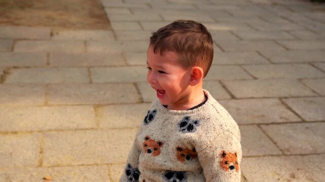 A happy young Latino child looks off-camera with a surprised and joyful expression in the gardens of Nara, Japan during winter. This static shot captures the child's innocent wonder.