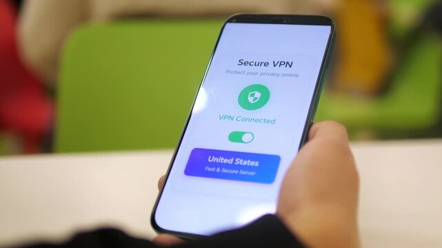 Person using Secure VPN app on smartphone for online privacy. Close-up of a hand holding a phone with a VPN connected to a US server. Concept of cyber security, data encryption, and safe internet