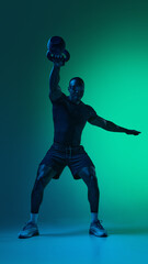 Naklejka premium Athlete performing single arm kettlebell press with futuristic visor in neon light. Concept of strength training exercise, balance control workout, tech inspired fitness routine