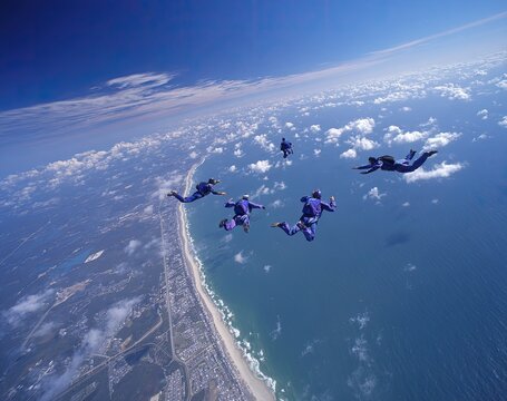 Thrill-seekers plummet above a coastline, skydiving in formation over the ocean