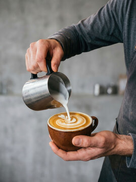 Barista pouring steamed milk into a coffee cup to create latte art