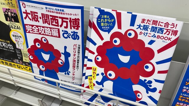 Expo 2025 Osaka Kansai guidebook and Myaku-Myaku mascot character books displayed on a store shelf rack featuring exhibition news and information - Osaka, Japan, August 28, 2024