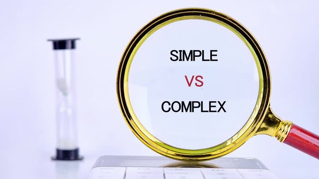 Fragmented letters slowly come together inside a magnifying glass to display Simple versus Complex, set on a white desk beside an active hourglass