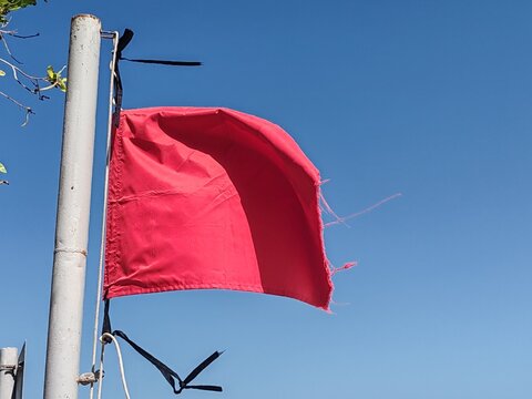 Red flag on a beach is No swimming sign.
Red flag on beach, which serves as a safety warning sign.
A red flags indicates high hazard conditions, such as strong surf, dangerous currents, or pollution.