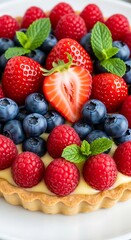 Obraz premium A delectable fruit tart adorned with a colorful assortment of fresh berries and mint leaves.
