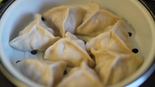 Close-up of steamed khinkali in a white ceramic steamer.