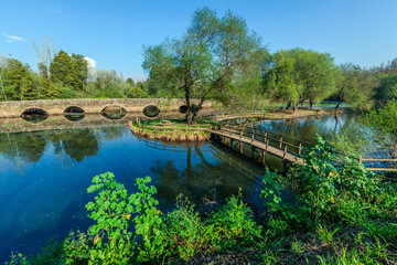 Fototapeta premium A portuguese medieval stone arch bridge of Marnel crosses a tranquil blue river