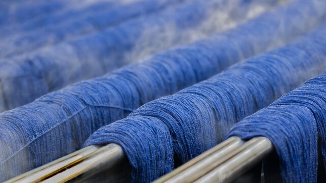 Blue Dyed Yarn Threads on Metal Rods in Textile Production Process