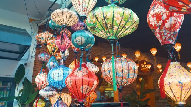 Colorful silk lanterns with intricate patterns hanging over a night street market, casting warm, glowing light and creating a vibrant, festive atmosphere rich in traditional asian charm