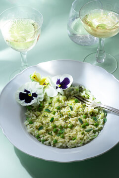 Light green spring risotto with peas and herbs, flowers. Spring menus, front view