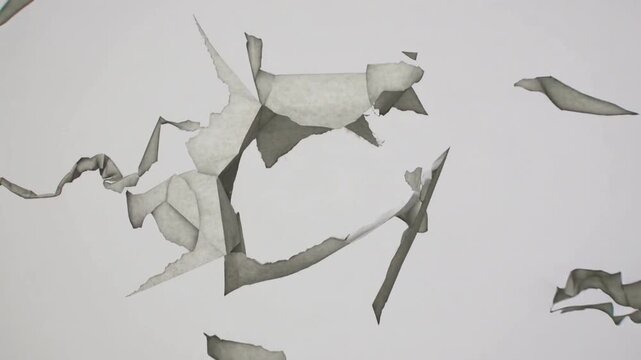 Rupture forming at center, taut horizontal cord tearing across gray backdrop, fragments drifting