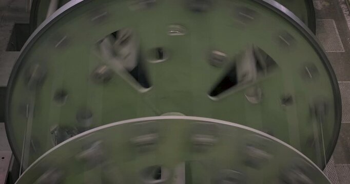 Close up of large rotating green cable reels in a wire rope manufacturing facility during production