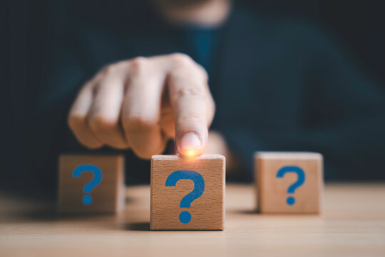 Question mark decision concept with hand select wooden block, symbolizing uncertainty, problem solving, critical thinking and choosing the right answer in business strategy and decision making process