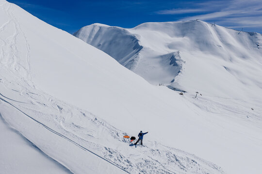Freeride skiers climbing and descending Bidara peak in Gudauri on deep fresh powder snow, winter adventure in Georgia mountains. Backcountry freeride and skiing untouched powder in snowy mountains