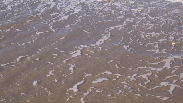 Close-up of waves on a sandy beach along the Mediterranean coast in Malaga, Andalusia, Spain.