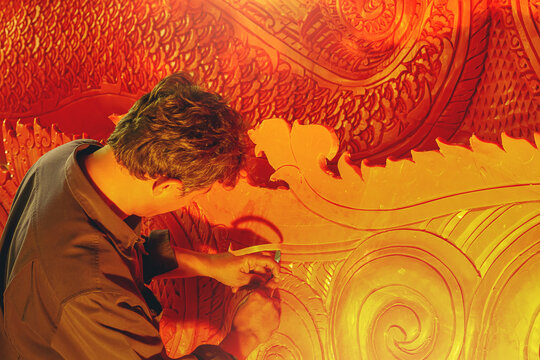 Artist using carving knife to carving candles for candle festival in Thailand.