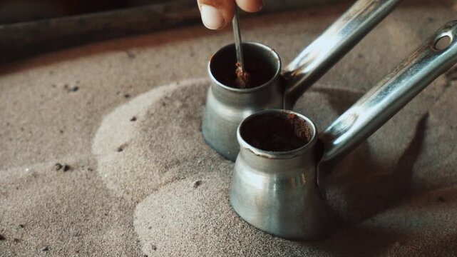 Traditional process of making Turkish coffee in a copper cezve on hot sand. Close-up of brewing coffee with foam rising, authentic oriental preparation method