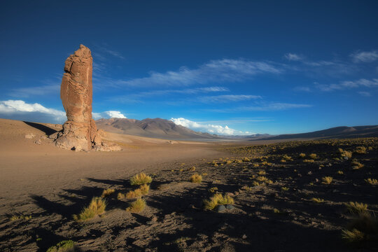 Tall volcanic rock monolith Monjes de la Pacana in Atacama Desert, Chile, under blue sky with golden hour lighting. Ideal for travel editorial, outdoor lifestyle, and nature conservation projects
