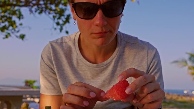 Close Up of Hands Holding Pomelo Slice and Separating Juicy Segments at Seaside Table in Warm Sunset Light, Healthy Eating Concept