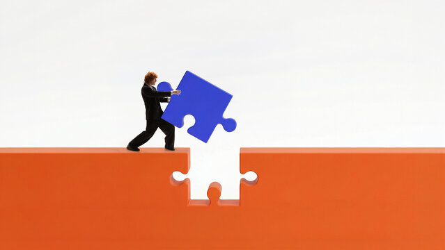 Businessman placing puzzle piece to bridge gap and complete connection. Concept of problem solving, teamwork effort, closing business gaps and achieving strategic alignment