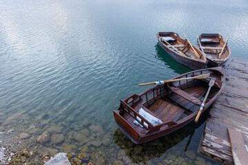 Obraz premium Wooden boats by the pier on a lake at sunset with mist rising over the water