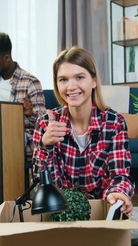 Close up of woman which sitting on the floor in front of camera and gesturing alright symbol when her serious busy african american man collecting rack with handheld screwdriver