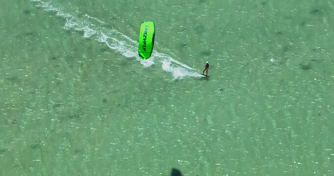 Aerial view of kitesurfer speeding with kite in clear crystal water. Kitesurfer rides a kite in the Indian Ocean. Live reef near island. Mauritius island 