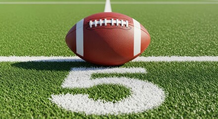 Obraz premium American football on green grass field with white yard line and number five.