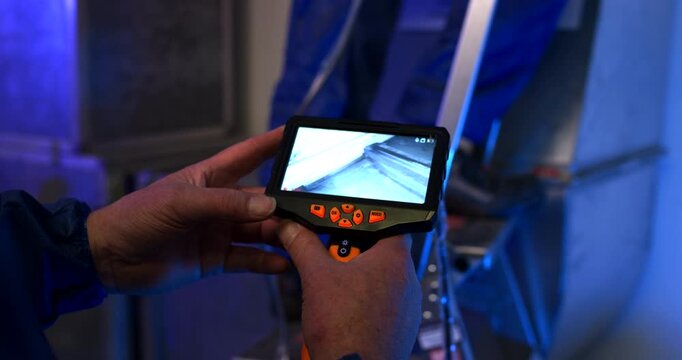 Close up of technician hands holding a digital display for industrial endoscope inspection in a workshop