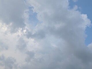 Fototapeta premium A detailed view of a cloudy sky with various shades of grey and white clouds against a backdrop of blue sky.