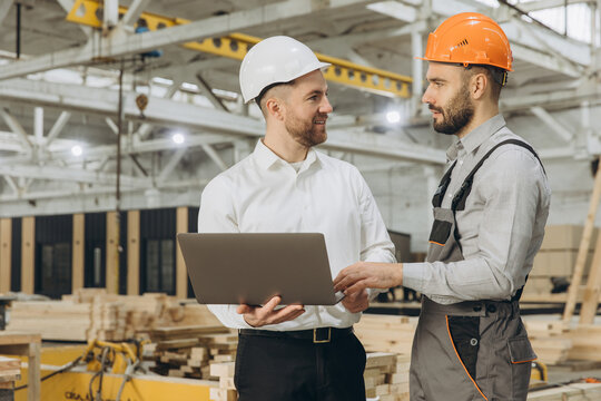 Engineers discussing project on laptop in modular building factory