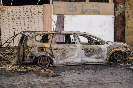 Burned out car wreck abandoned on city street. Destroyed vehicle after fire accident. Vehicle hulk as result of war conflict or arson. Urban catastrophe and property damage concept.