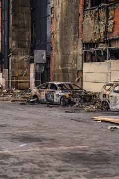 Burned out car wreck abandoned on city street. Destroyed vehicle after fire accident. Vehicle hulk as result of war conflict or arson. Urban catastrophe and property damage concept.