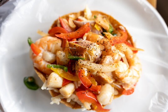 Colorful seafood ceviche served on a crispy tostada, topped with shrimp, peppers, onions, and spices
